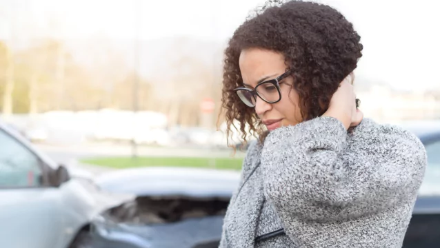 A woman stands at the scene of a wreck, looks down and puts her hand behind her neck. Silver & Archibald can help you find a respected Georgia personal injury lawyer.
