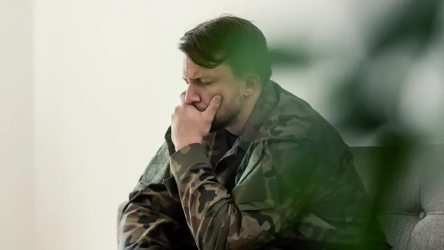 A soldier in fatigues sits on a couch, closing his eyes and resting his chin in his hand. Veterans’ Disability lawyers from Silver & Archibald help Georgians get the maximum benefits.