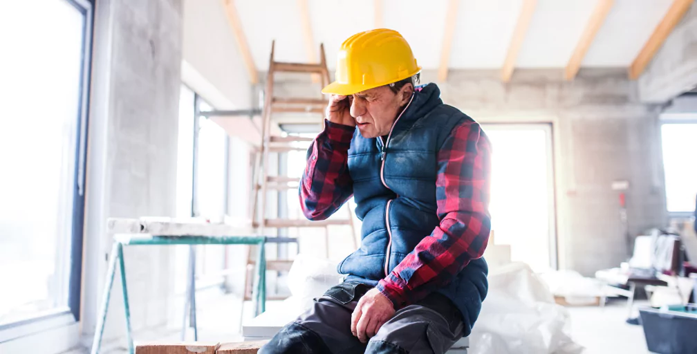 In a room under construction, a man in hardhat sits down, closes his eyes and puts his hand to his forehead, as though he’s hurt. For job injuries, talk to the Georgia workers’ comp lawyers at Silver & Archibald.