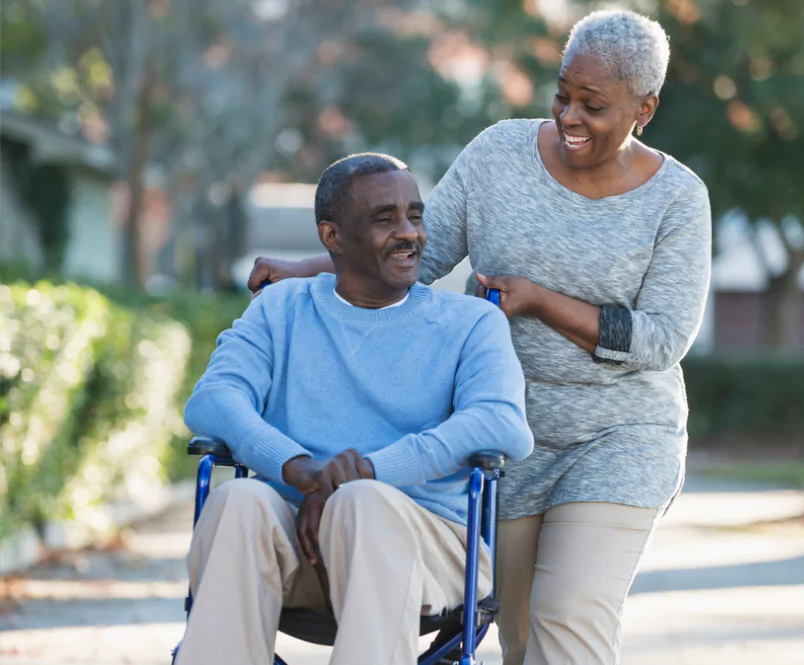 Out on a walk, a woman pushes a man in wheelchair as they talk and smile. You can appeal a long-term disability denial with help from LTD lawyers.