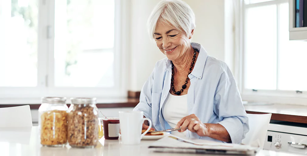 A woman over 65 looking down and reading documents.